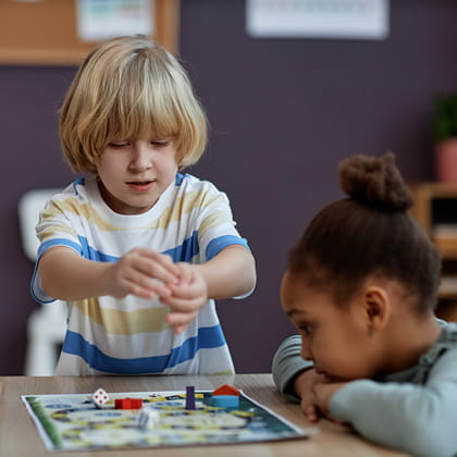A young boy and a young girl are playing a board game together.