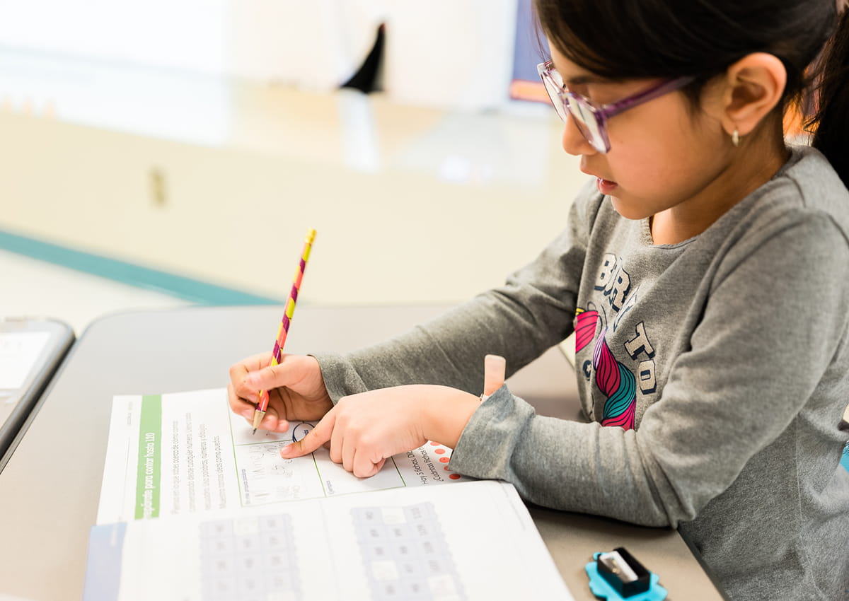 Student practicing math problems at a desk.