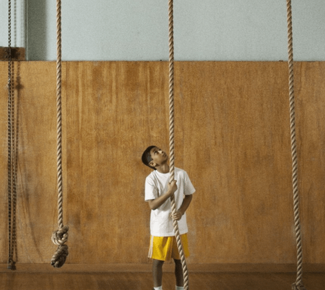 Young boy preparing to climb up rope.