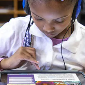 Student wearing headphones looking at a tablet.