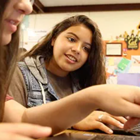 Two students working together on laptops.