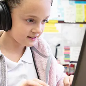 Student wearing headphones looking at a laptop.