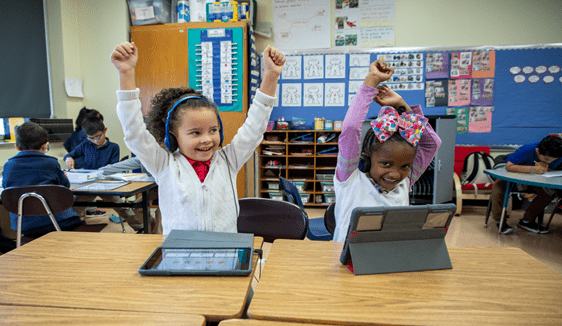 Two smiling i-Ready students holding their arms in the air and smiling