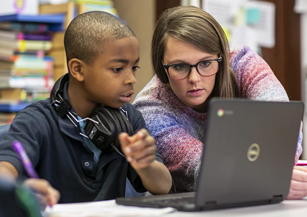 A teacher and student working together at a laptop.