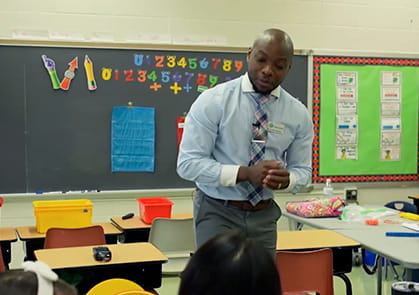The author, Jesse Lewis, is standing at the head of the class, instructing his students.