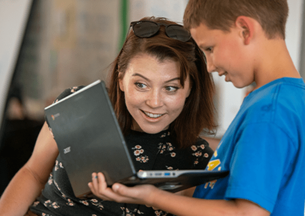 An educator and student looking at a laptop.