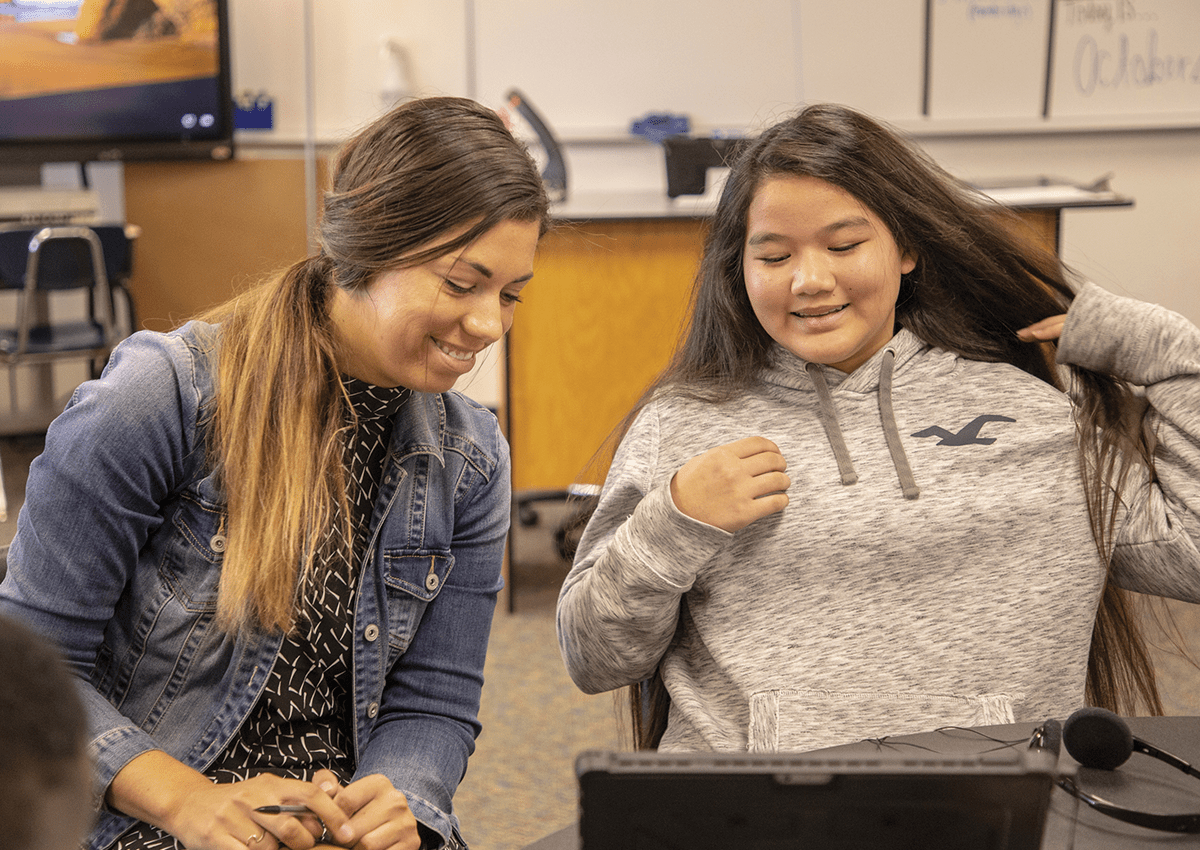 A teacher and her student connect while viewing a laptop screen.