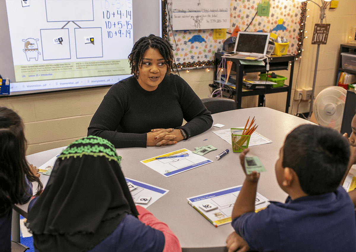A teacher explains a math concept to a group of students during an interactive lesson.