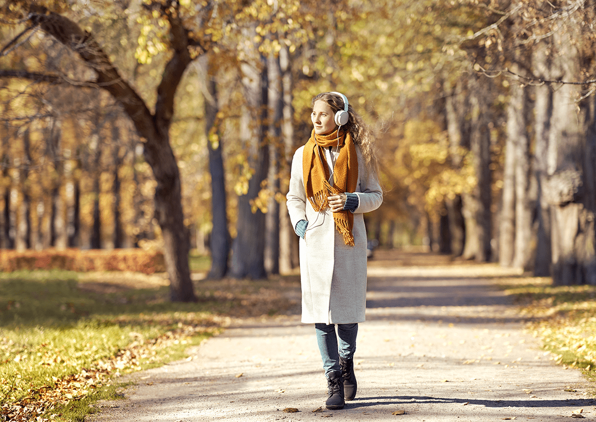 An educator wearing headphones enjoys a fall walk.