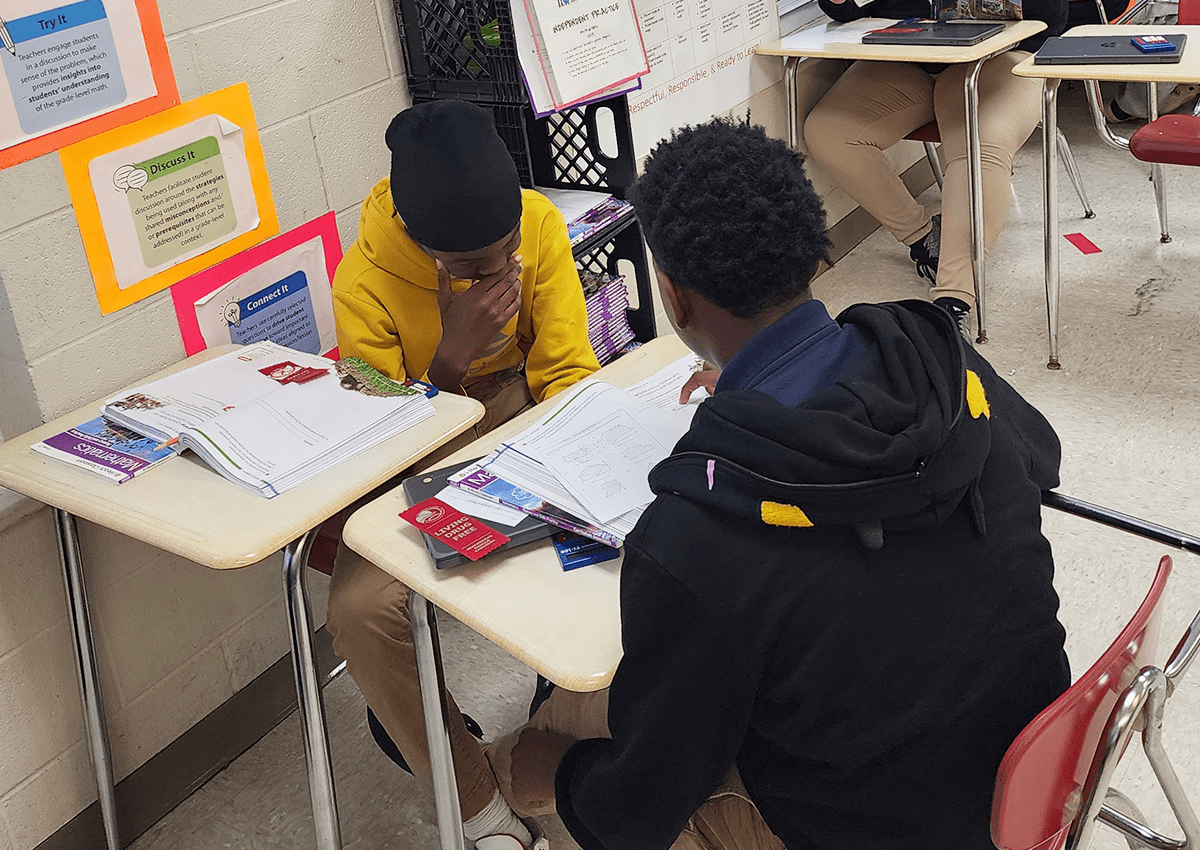 Two middle school students collaborate on a mathematics assignment.