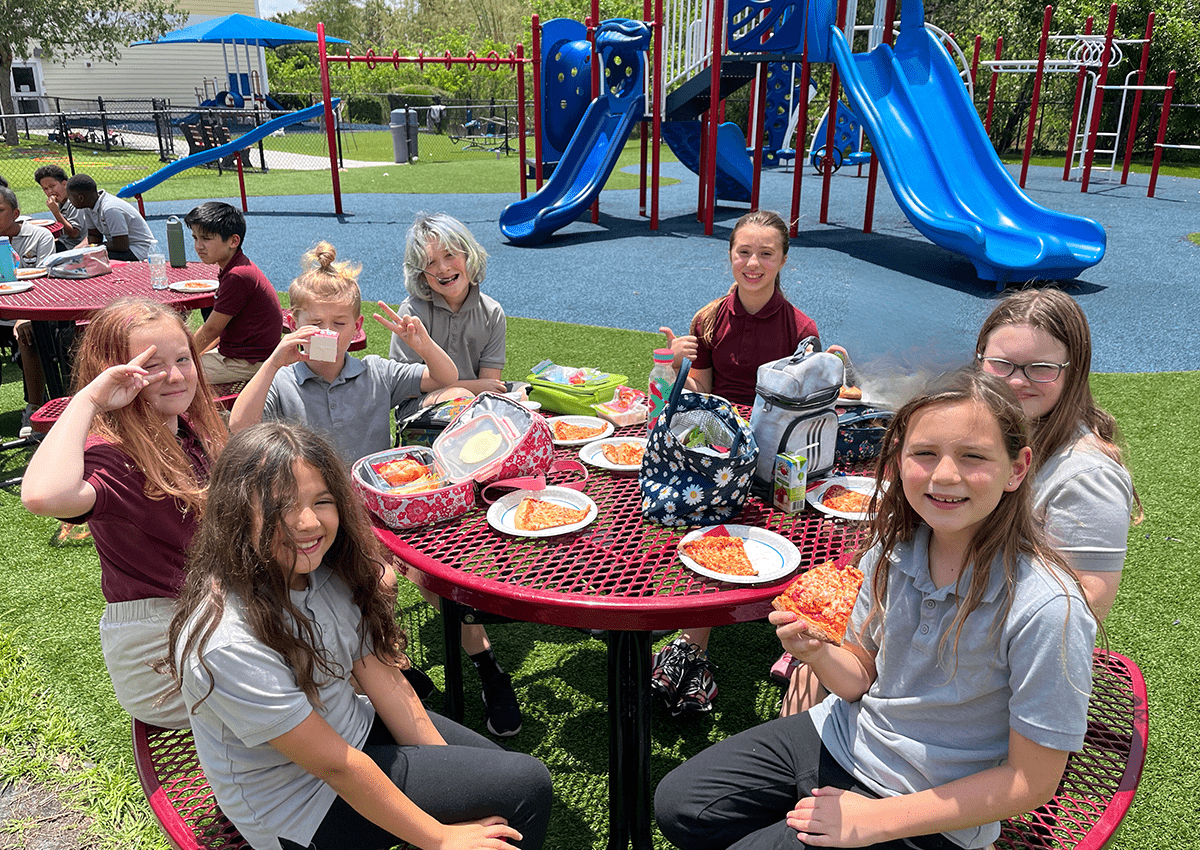 A group of students are enjoying their lunch outdoors on the playground.