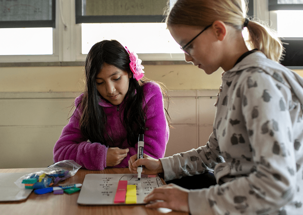 Two young girls partnered together use manipulatives during a math lesson on fractions.